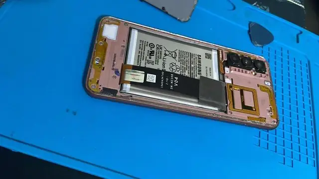 Celular Samsung aberto sobre a manta de bancada, com a bateria à mostra